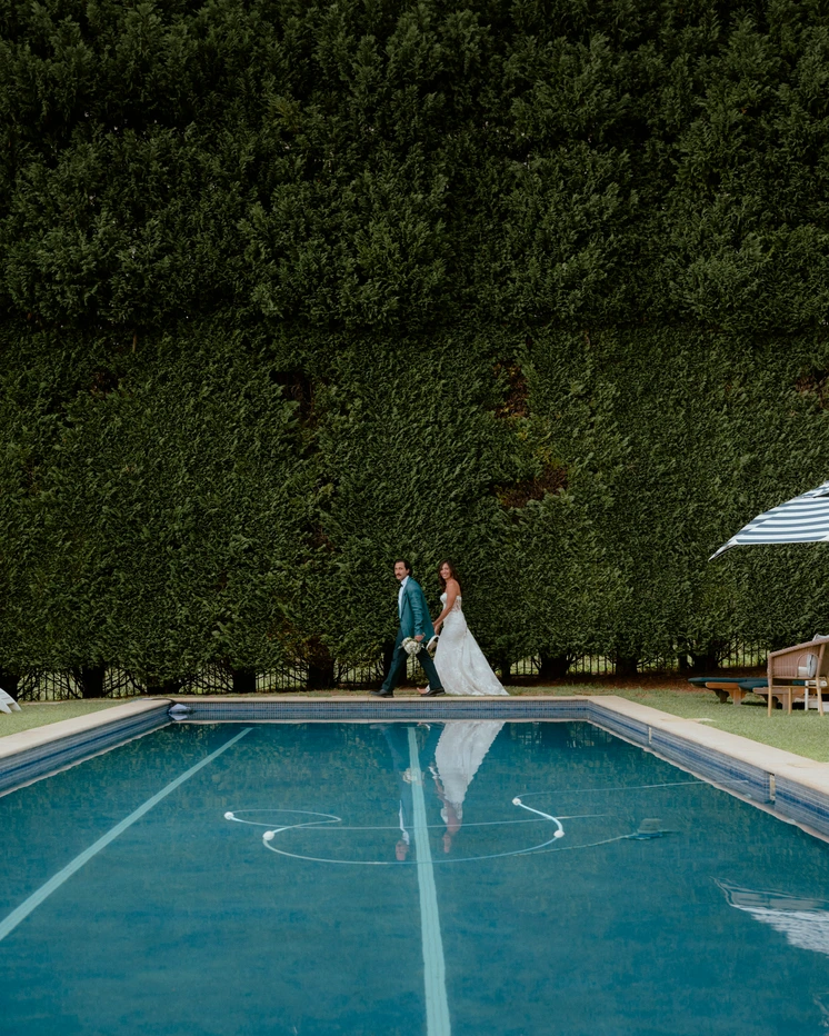 Couple walking by a pool at their wedding